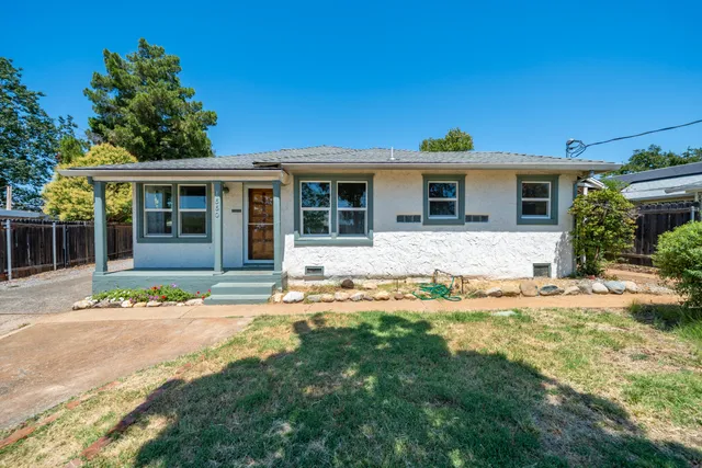 a front view of a house with a yard and potted plants