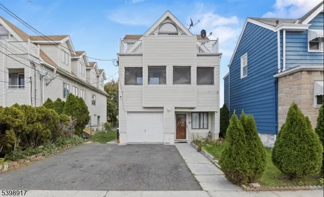 a view of a white building among the plants and large tree