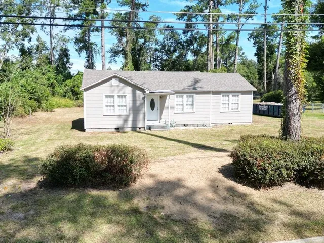 a view of a house with a big yard and large tree