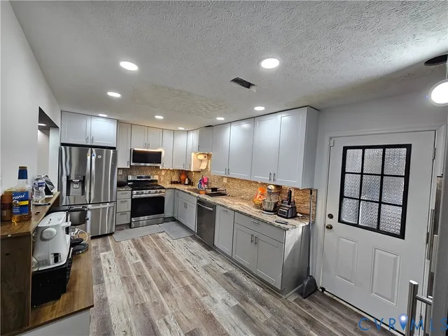 a kitchen with stainless steel appliances kitchen island granite countertop a refrigerator and a sink