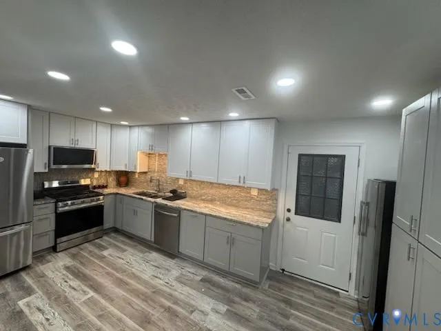 a large kitchen with stainless steel appliances lots of counter space and a sink