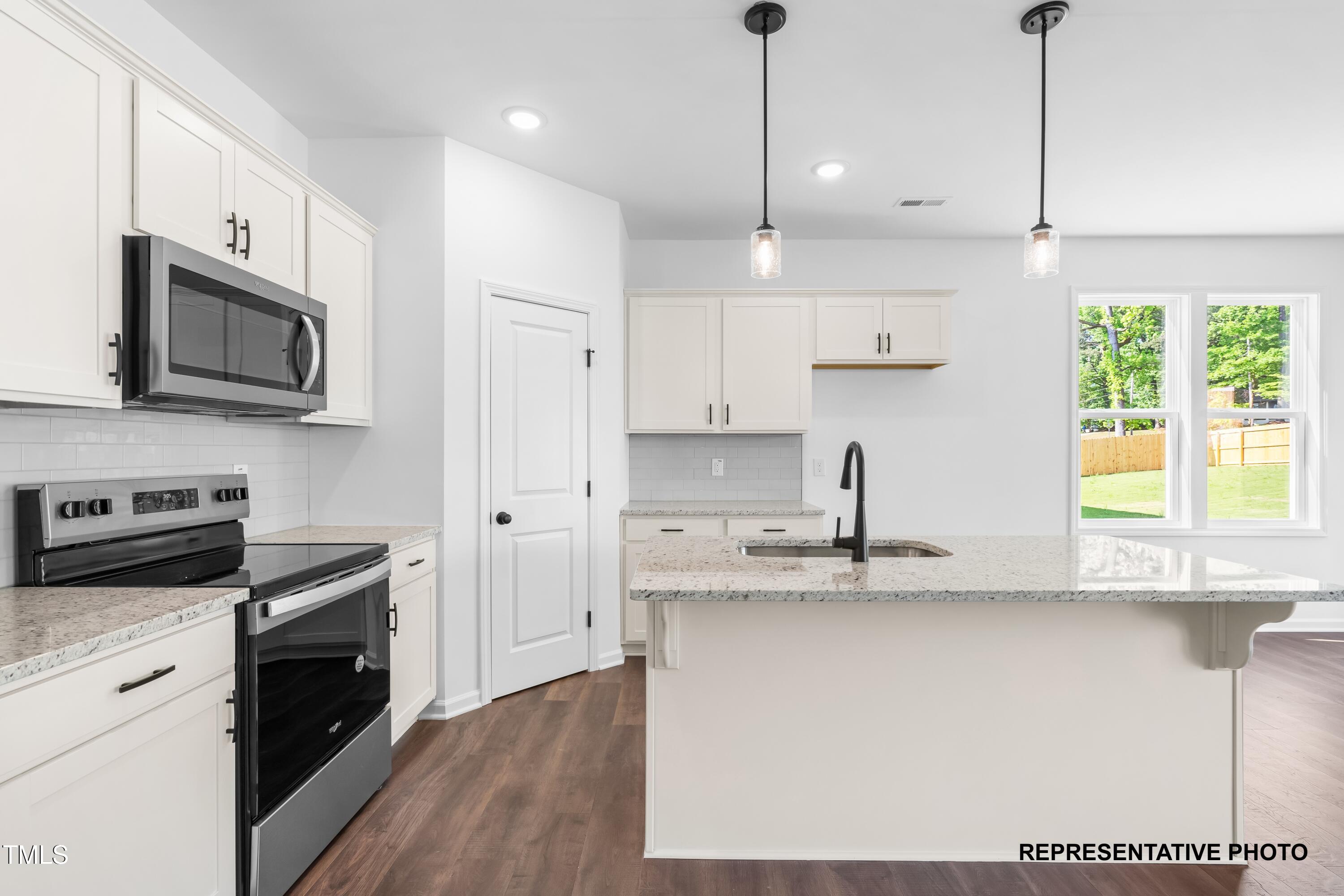 280 Bluejay Street Clayton, NC 27520 - Photo 2 of 14 a kitchen with stainless steel appliances granite countertop a sink a stove a refrigerator and island with wooden floor