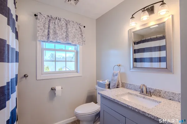a bathroom with a granite countertop toilet a sink and a mirror