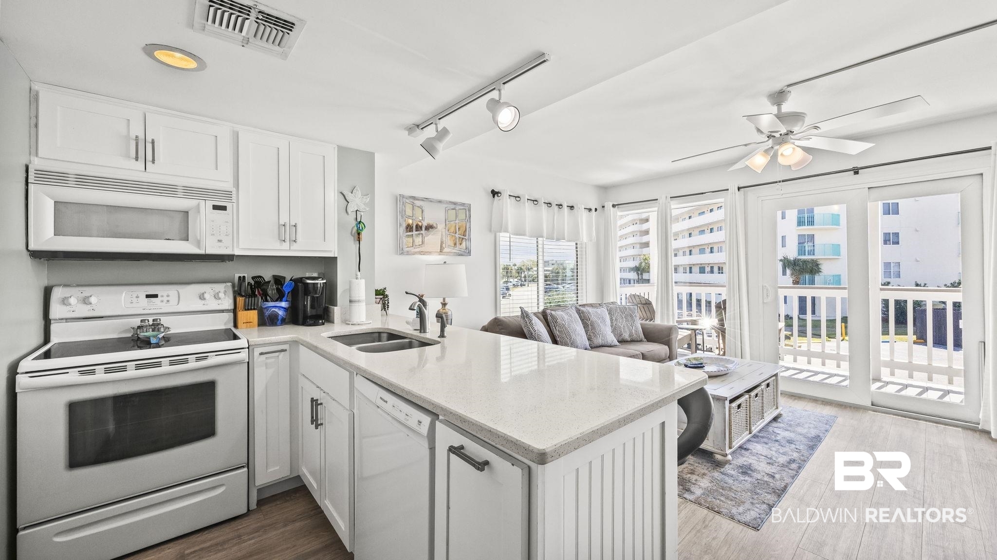 497 Plantation Road, Unit 1247 Gulf Shores, AL 36542 - Photo 27 of 29 Kitchen with a peninsula, white appliances, light stone countertops, open floor plan, and white cabinetry