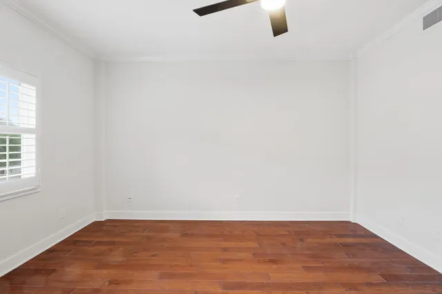 an empty room with wooden floor cabinet and windows