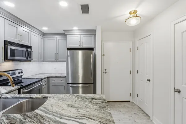 a kitchen with stainless steel appliances granite countertop a refrigerator a stove and a sink