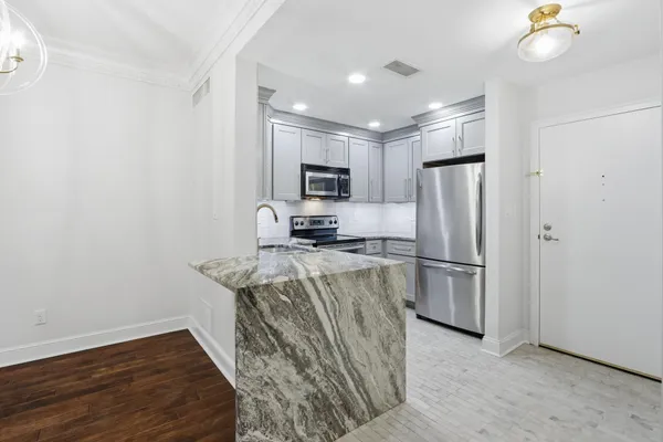 a kitchen with stainless steel appliances granite countertop a refrigerator a stove a sink a microwave oven with white cabinets and wooden floor