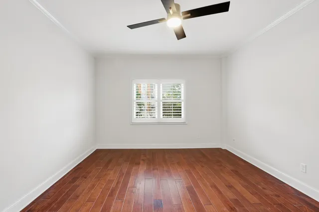 an empty room with wooden floor cabinet and windows