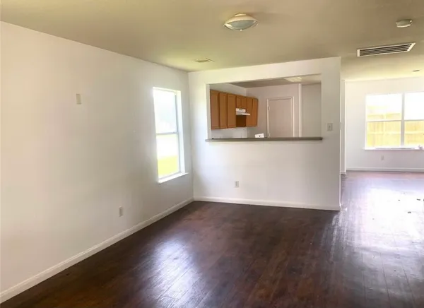 an empty room with wooden floor and windows