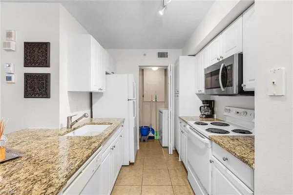 a kitchen with granite countertop a sink stove and refrigerator