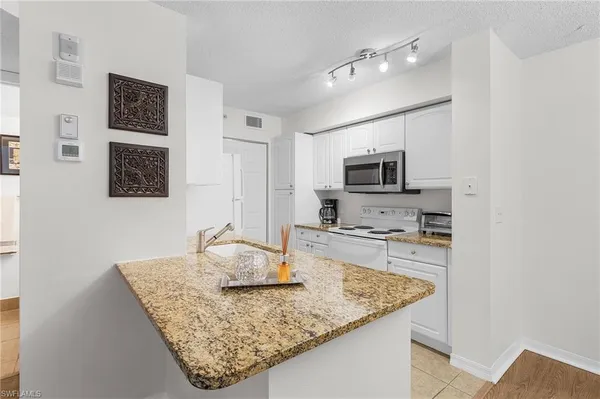 a kitchen with stainless steel appliances granite countertop a sink refrigerator stove and microwave