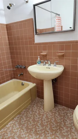 a bathroom with a sink a bathtub and mirror
