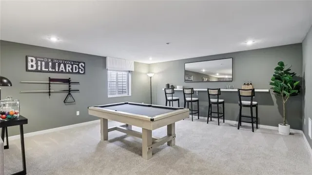 a room with stainless steel appliances kitchen island a table chairs and a refrigerator