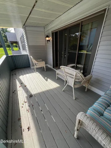 a balcony with wooden floor and outdoor seating