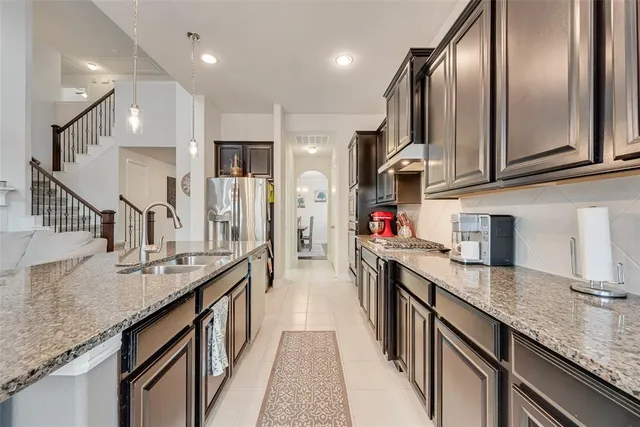 a kitchen with stainless steel appliances granite countertop a sink dishwasher a stove and a refrigerator with wooden floor