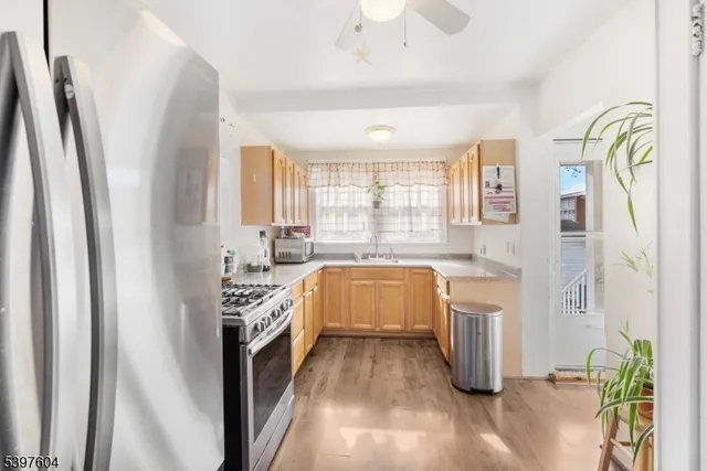 a kitchen with stainless steel appliances granite countertop a refrigerator a sink a stove and white countertops with wooden floor