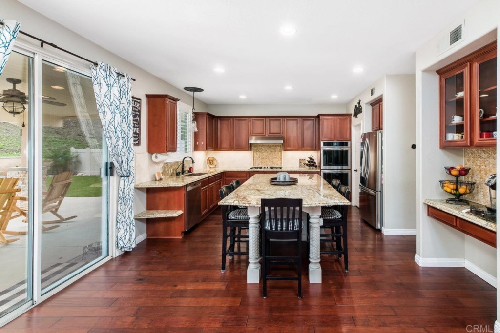 34063 Abbey Road Temecula, CA 92592 - Photo 3 of 33 a open kitchen with stainless steel appliances granite countertop a refrigerator stove top oven and a dining table with wooden floor