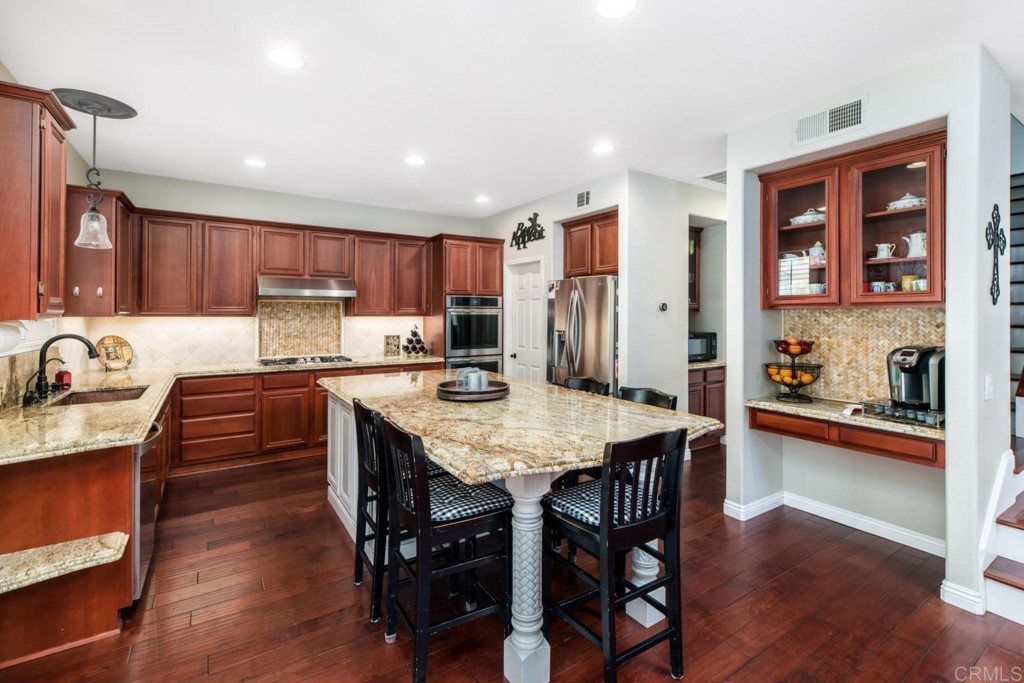 34063 Abbey Road Temecula, CA 92592 - Photo 4 of 33 a kitchen with stainless steel appliances granite countertop a table chairs sink refrigerator and cabinets