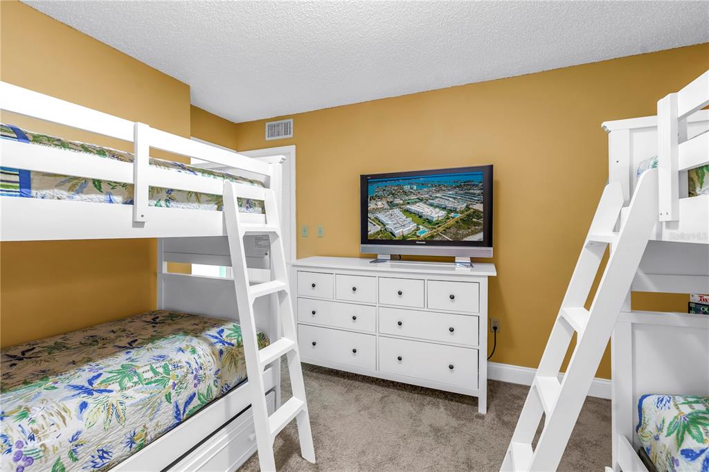 6600 Sunset Way, Unit 118 St. Pete Beach, FL 33706 - Photo 36 of 64 a view of bedroom with furniture and flat screen tv