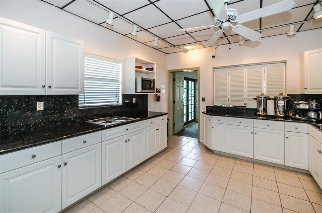 6600 Sunset Way, Unit 118 St. Pete Beach, FL 33706 - Photo 53 of 64 a large kitchen with granite countertop a sink a stove counter space and cabinets