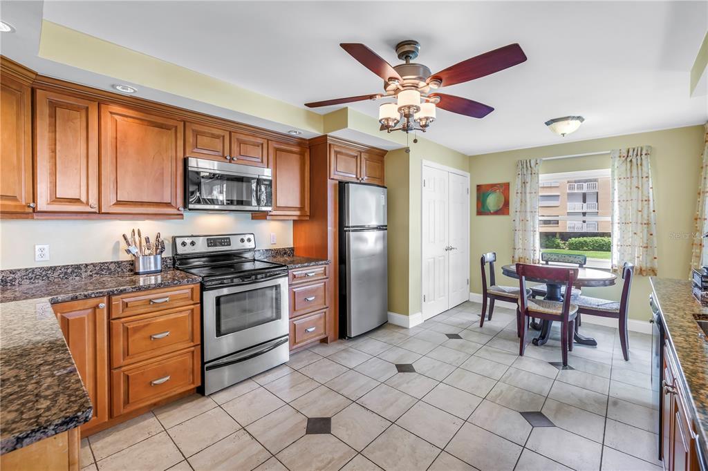 6600 Sunset Way, Unit 118 St. Pete Beach, FL 33706 - Photo 7 of 64 a kitchen with stainless steel appliances granite countertop a stove top oven a sink dishwasher a dining table and chairs with wooden floor