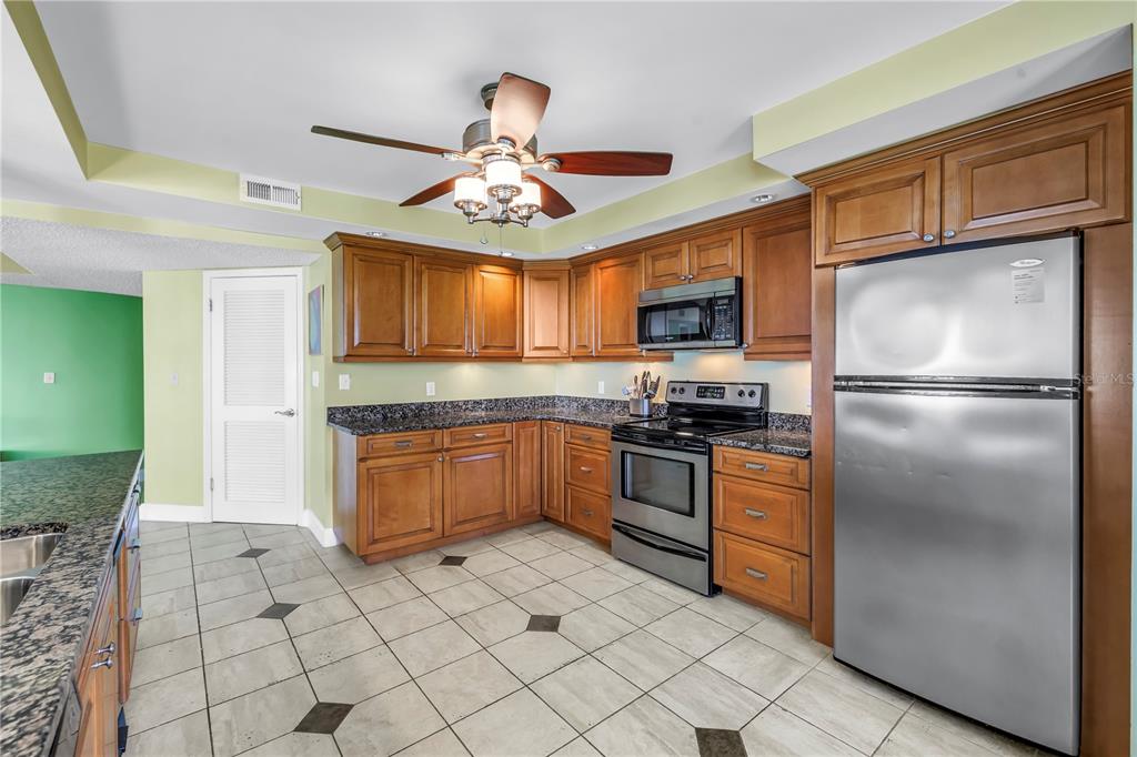 6600 Sunset Way, Unit 118 St. Pete Beach, FL 33706 - Photo 9 of 64 a kitchen with granite countertop stainless steel appliances and wooden cabinets