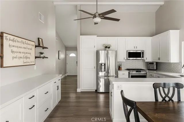 a kitchen with stainless steel appliances granite countertop a refrigerator a stove a sink a dining table and chairs with wooden floor