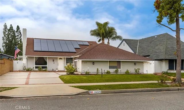 a front view of a house with a garden and trees