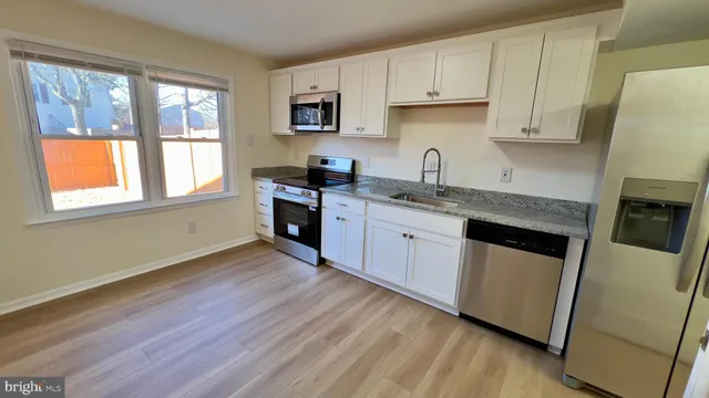 a kitchen with stainless steel appliances granite countertop wooden floors a stove a microwave a sink and dishwasher with wooden floor