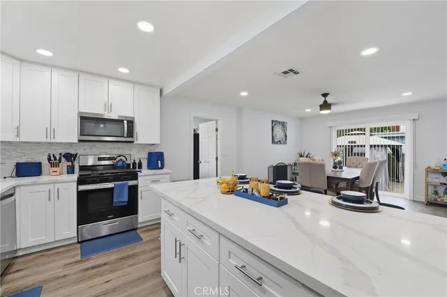 a kitchen view with wooden floor and stainless steel appliances