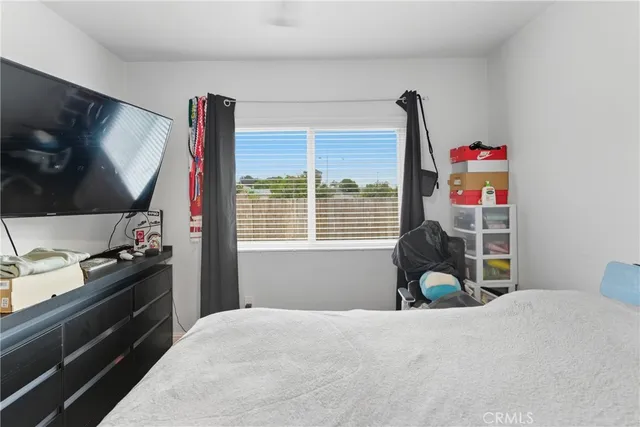 a bedroom with a bed and a flat tv screen on dresser