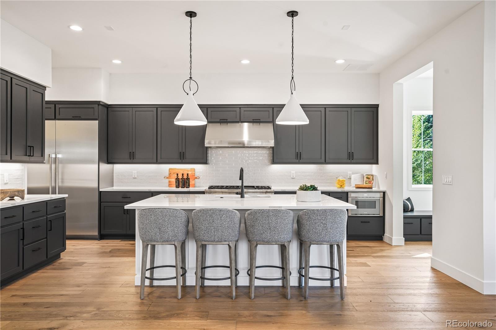 1067 South Cook Street Denver, CO 80209 - Photo 11 of 35 a kitchen with stainless steel appliances a dining table chairs sink and wooden floor