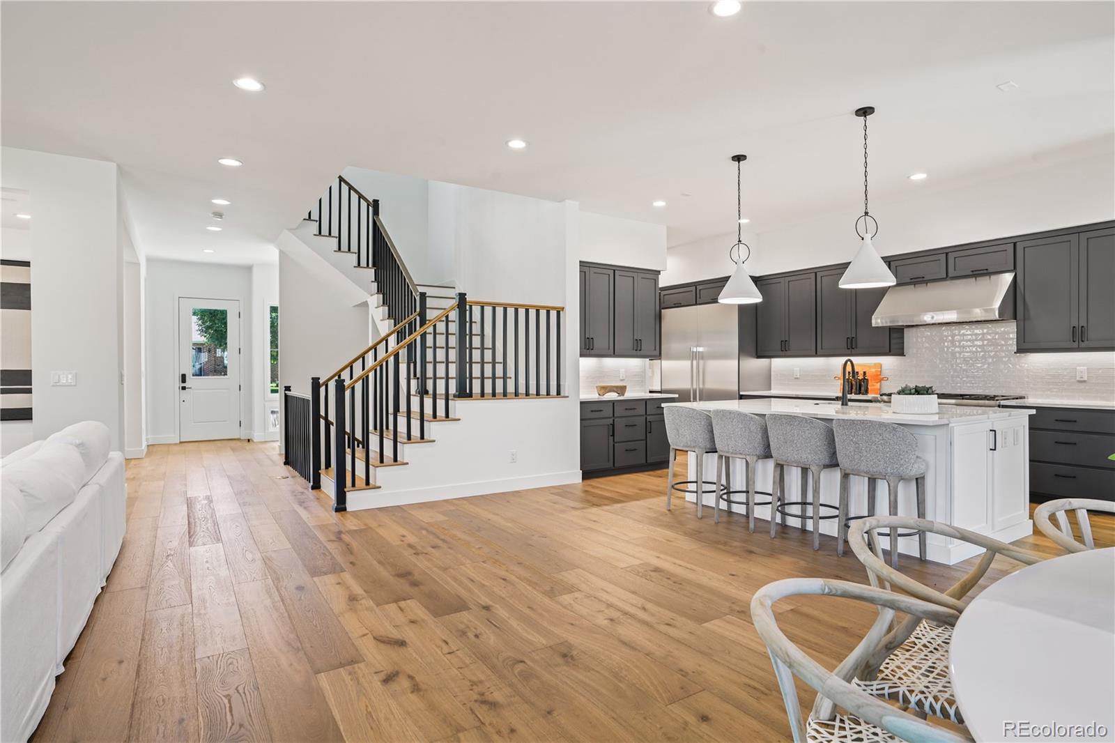 1067 South Cook Street Denver, CO 80209 - Photo 14 of 35 a open kitchen with stainless steel appliances kitchen island granite countertop a table chairs and a wooden floor