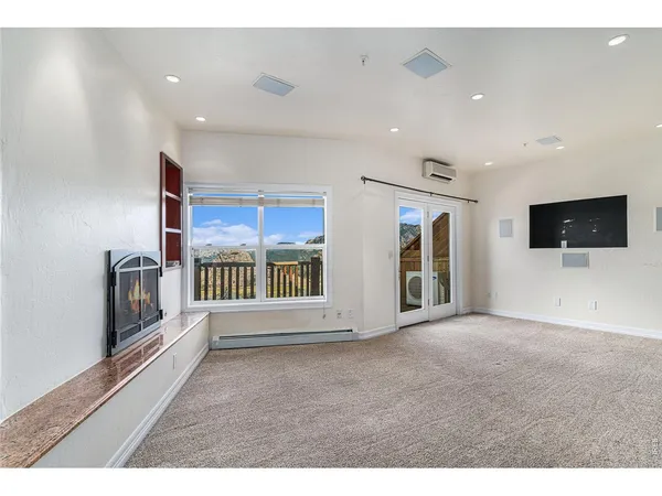 a view of an empty room with a window and a kitchen