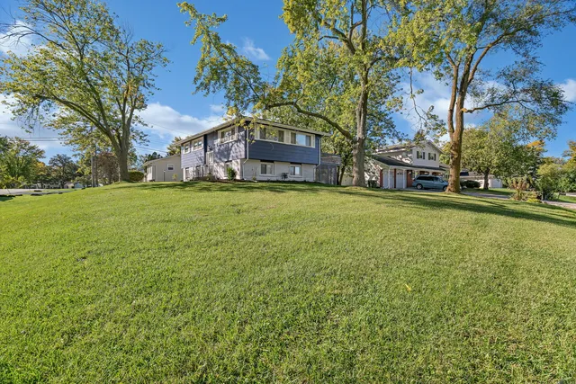 a view of a house with a yard and large trees