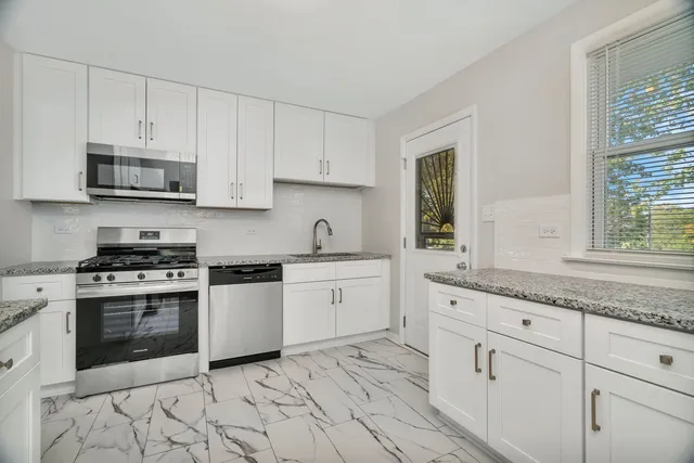 a kitchen with granite countertop white cabinets white stainless steel appliances with a sink and dishwasher