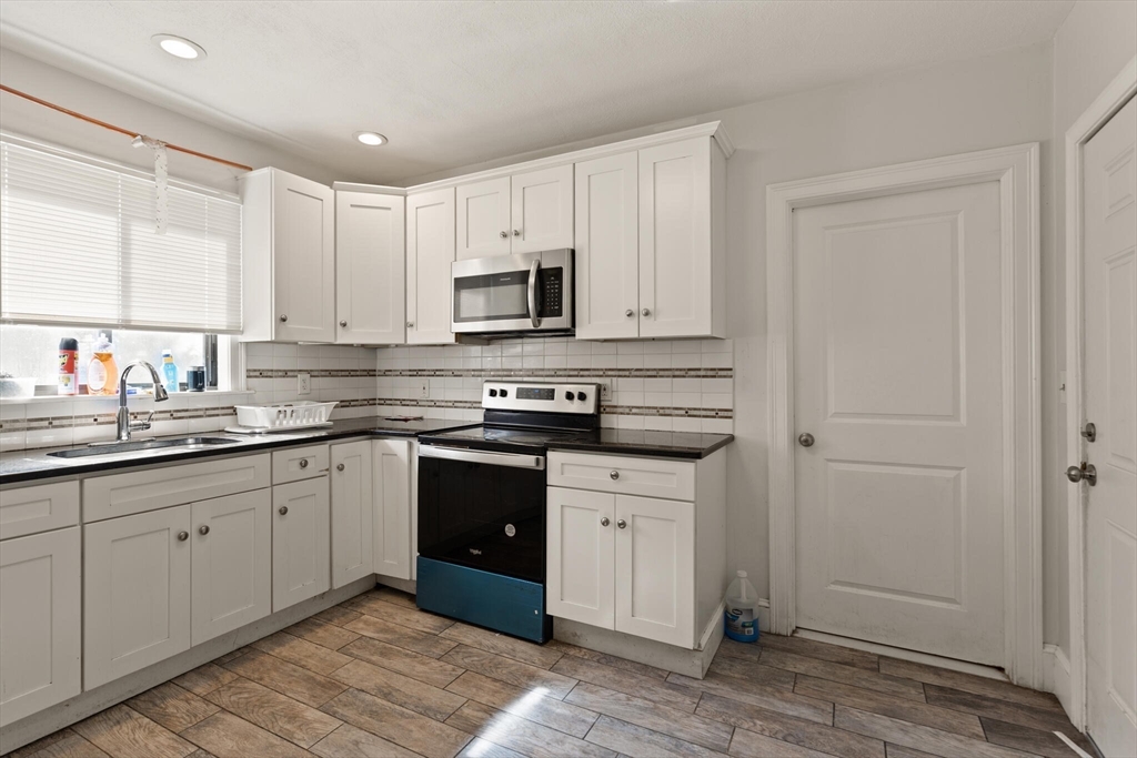 112 Johnson Street Lynn, MA 01902 - Photo 25 of 28 a kitchen with stainless steel appliances granite countertop a stove a sink and a refrigerator