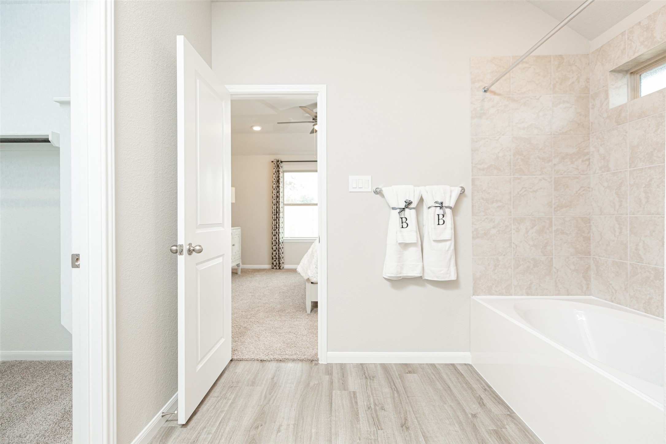 19555 Montgomery Rdg Way Montgomery, TX 77316 - Photo 19 of 21 A spacious primary master bath featuring a stylish vanity with light-colored countertops, offering a clean and elegant look. The bath includes a shower-tub combination with a beautifully tiled surround, creating a relaxing and functional space for daily use. Sample photo of completed home with similar floor plan. As-built interior colors and selections may vary.