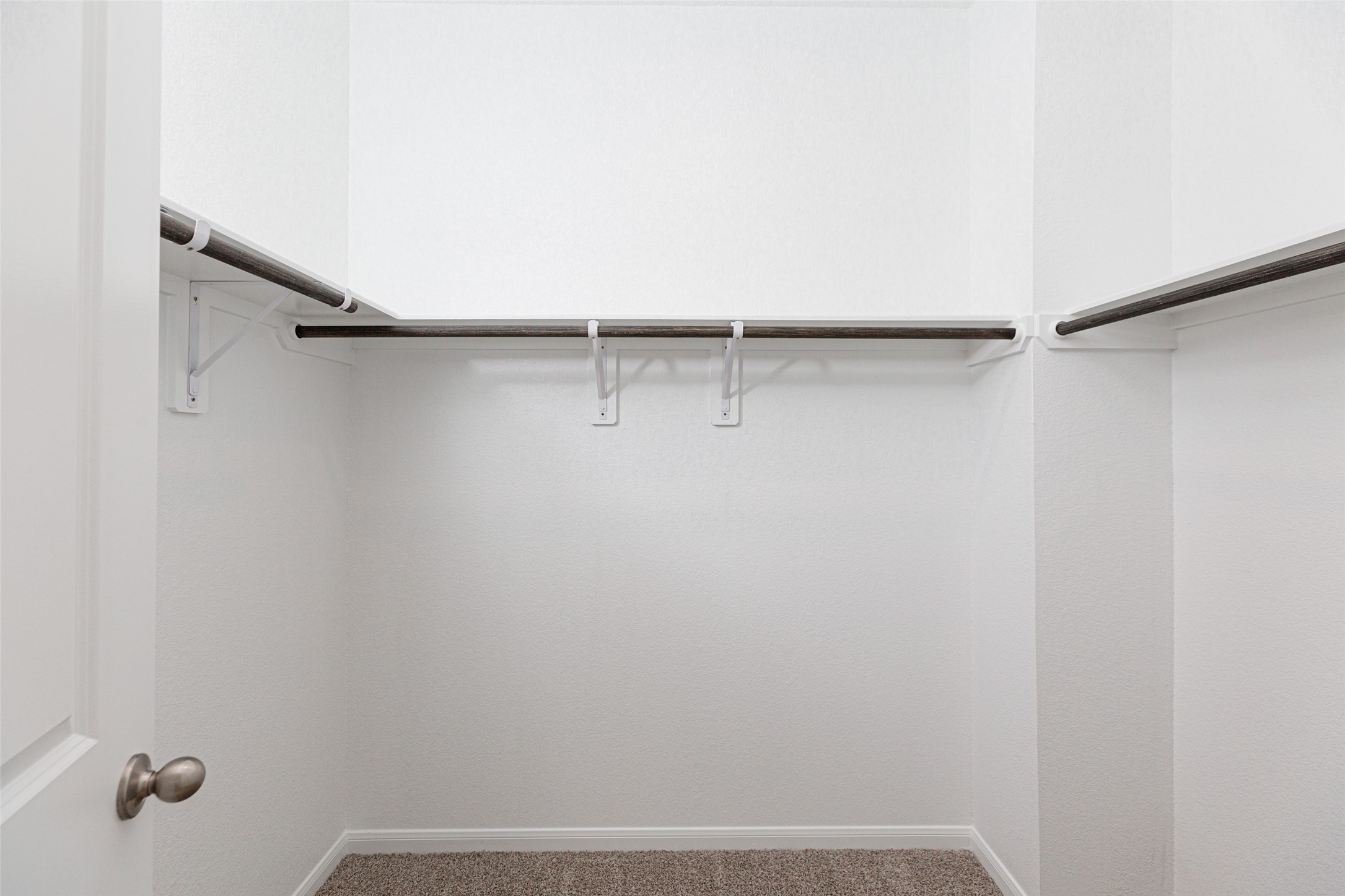 19555 Montgomery Rdg Way Montgomery, TX 77316 - Photo 20 of 21 Walk-in closet with high ceilings and plush carpet. Warm paint tones, built-in shelving, and dark finishes create a contemporary and functional retreat. Sample photo of completed home with similar floor plan. As-built interior colors and selections may vary.