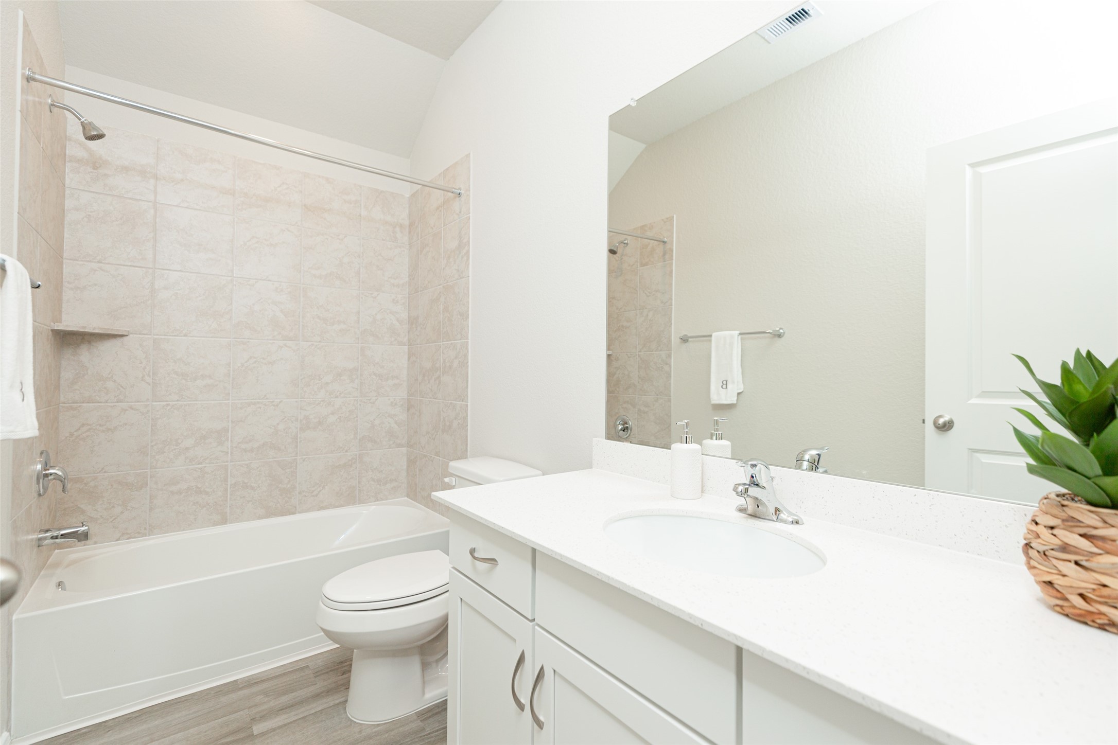 19555 Montgomery Rdg Way Montgomery, TX 77316 - Photo 21 of 21 Secondary bathroom featuring a stylish vanity with light-colored countertops, offering a clean and elegant look. The bath includes a shower-tub combination with a beautifully tiled surround, creating a relaxing and functional space for daily use. Sample photo of completed home with similar floor plan. As-built interior colors and selections may vary.