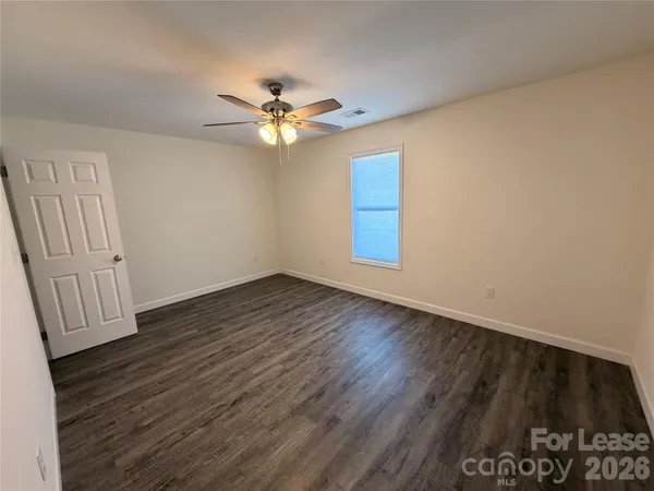 an empty room with wooden floor fan and windows