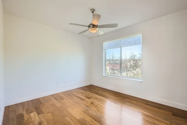 a view of a room with wooden floor and a ceiling fan