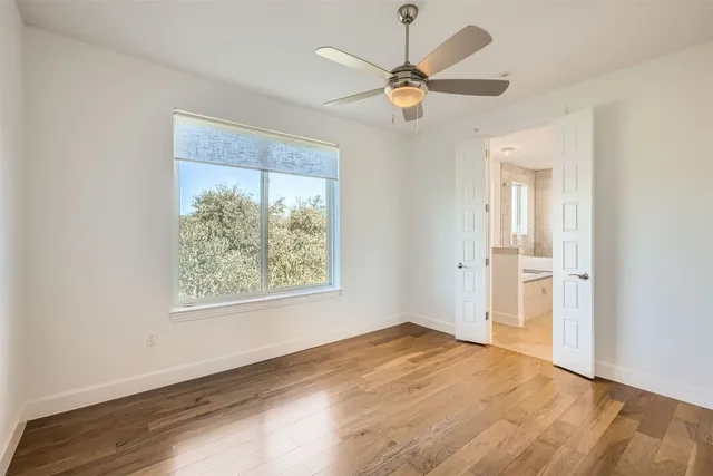 an empty room with windows and fan