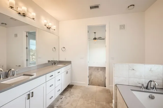 a spacious bathroom with a tub sink and mirror