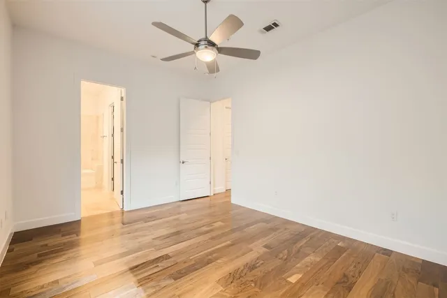 an empty room with wooden floor fan and windows