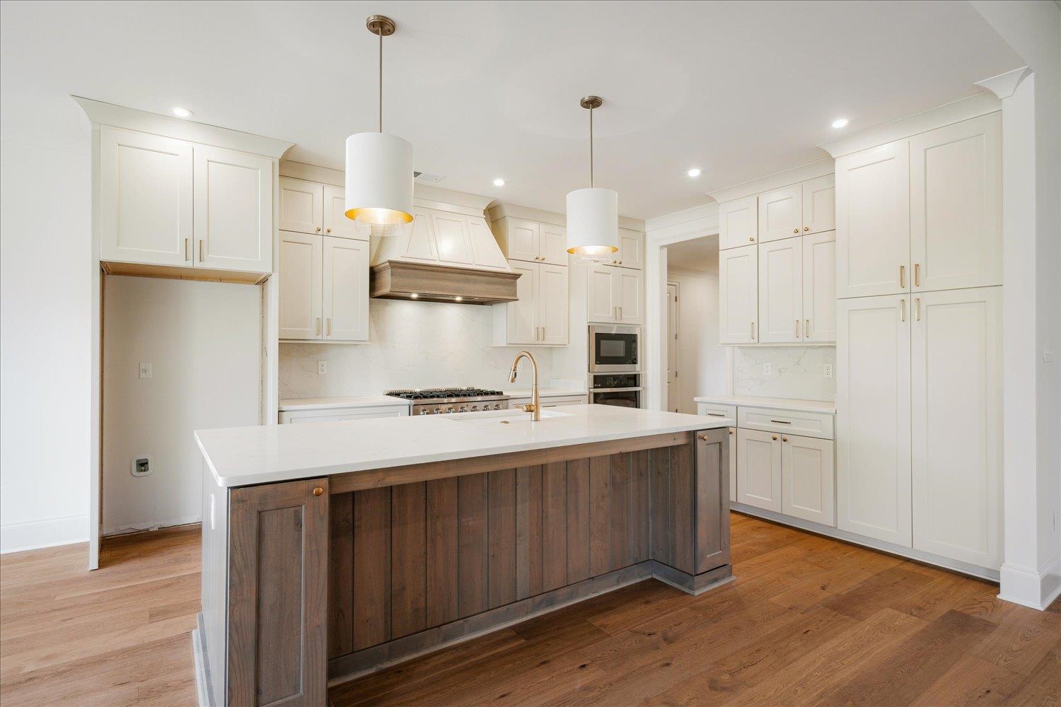12600 Miss Cloud Road Collierville, TN 38017 - Photo 12 of 40 Kitchen featuring light countertops, light wood-style flooring, premium range hood, built in microwave, and backsplash