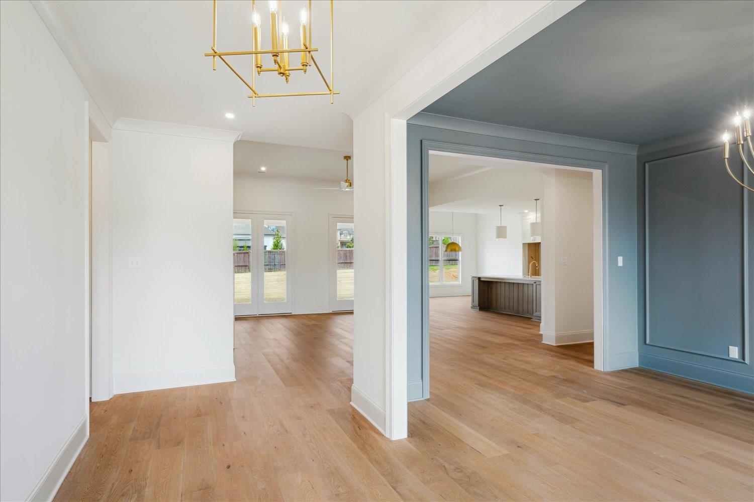 Corridor with light wood-style flooring, baseboards, and a chandelier