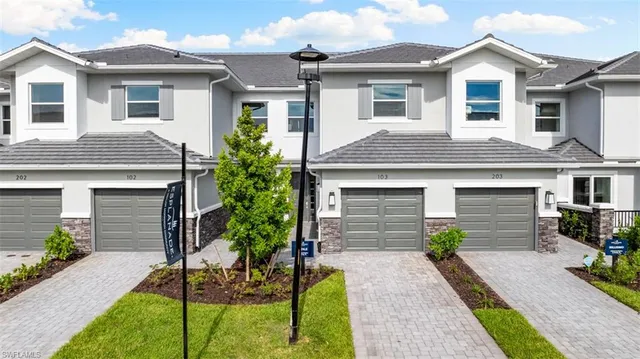 a front view of a house with a yard and potted plants