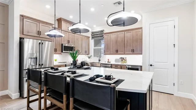 a kitchen with stainless steel appliances a stove a sink a refrigerator and chairs