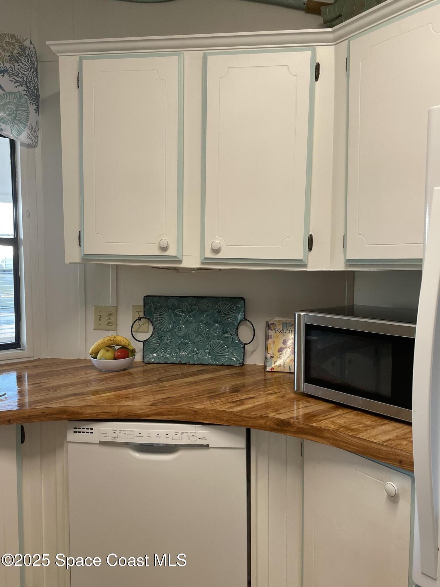 505 Puffin Drive Barefoot Bay, FL 32976 - Photo 6 of 8 a kitchen with granite countertop white cabinets and black appliances